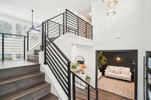 Stairway with a wealth of natural light, hardwood / wood-style floors, and a notable chandelier