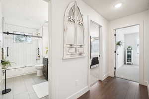 Full bathroom with a textured ceiling, shower / bath combination with glass door, toilet, vanity, and hardwood / wood-style flooring