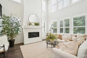 Living room featuring dark wood-type flooring, a large fireplace, and a wealth of natural light