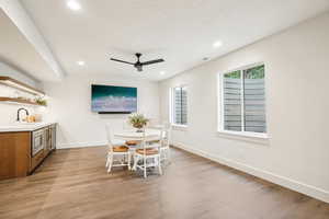 Dining room with a textured ceiling, sink, light wood-type flooring, and ceiling fan