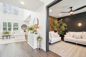 Living room with ceiling fan, a textured ceiling, a towering ceiling, and dark hardwood / wood-style flooring