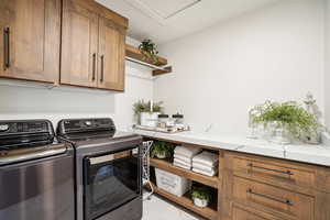 Laundry room featuring independent washer and dryer, light tile patterned floors, and cabinets