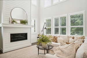 Living room with a towering ceiling, wood-type flooring, a large fireplace, and plenty of natural light