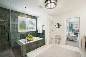 Bathroom with vanity, a textured ceiling, independent shower and bath, and a wealth of natural light