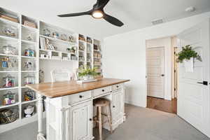 Carpeted office featuring ceiling fan