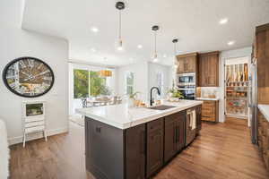 Kitchen featuring sink, appliances with stainless steel finishes, wood-type flooring, and an island with sink