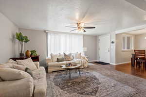 Living room featuring dark hardwood / wood-style floors, a textured ceiling, and ceiling fan