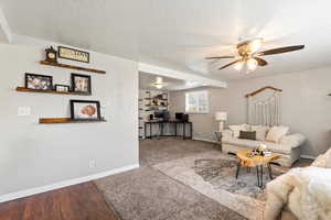 Living room featuring a textured ceiling, hardwood / wood-style flooring, and ceiling fan