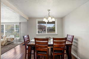 Dining space with dark wood-type flooring, a textured ceiling, and a chandelier