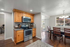 Kitchen featuring a chandelier, appliances with stainless steel finishes, decorative light fixtures, and dark hardwood / wood-style flooring