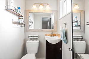 Bathroom featuring toilet, vanity, and a wealth of natural light