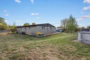 Back of property featuring central air condition unit and a lawn