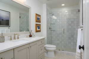 Bathroom with vanity, a shower with shower door, toilet, and tile patterned floors