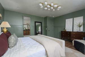 Bedroom with a textured ceiling, ensuite bathroom, and wood-type flooring