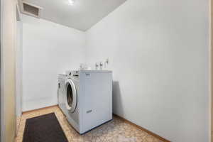 Clothes washing area with light tile patterned flooring and washing machine and clothes dryer