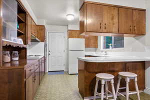 Kitchen with a breakfast bar, white fridge, and kitchen peninsula