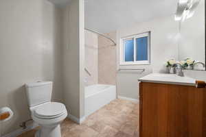 Full bathroom with toilet, tiled shower / bath combo, and vanity