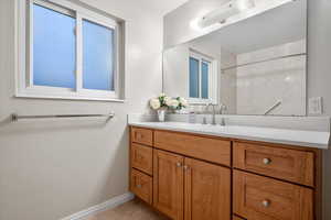 Bathroom with vanity, walk in shower, and tile patterned flooring