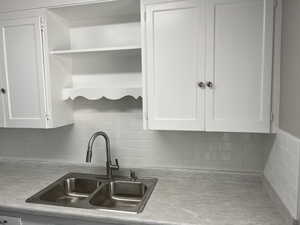 Kitchen featuring white cabinetry, sink, and backsplash