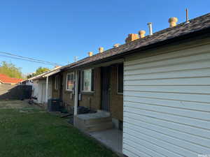 Rear view of house featuring central air condition unit and a lawn