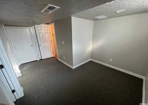 Carpeted empty room with a textured ceiling