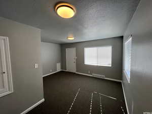 Carpeted empty room featuring a textured ceiling