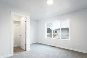 Unfurnished bedroom with a spacious closet, a closet, and light colored carpet