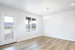 Unfurnished dining area with light hardwood / wood-style flooring, a mountain view, a healthy amount of sunlight, and a chandelier