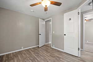 Unfurnished bedroom with light hardwood / wood-style flooring, a textured ceiling, and ceiling fan