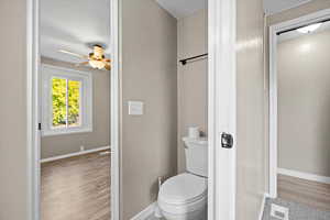 Bathroom featuring toilet, wood-type flooring, a textured ceiling, and ceiling fan