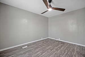 Empty room featuring dark hardwood / wood-style floors and ceiling fan