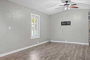 Unfurnished room featuring hardwood / wood-style flooring, ceiling fan, and vaulted ceiling