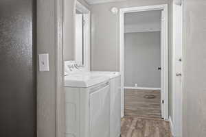 Clothes washing area with light wood-type flooring and washing machine and clothes dryer