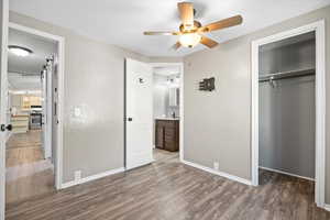 Unfurnished bedroom with a closet, dark wood-type flooring, ensuite bathroom, a textured ceiling, and ceiling fan