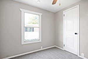 Carpeted empty room featuring ceiling fan