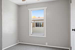 Carpeted empty room featuring ceiling fan