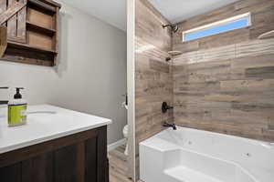 Full bathroom featuring toilet, tiled shower / bath, a textured ceiling, and vanity