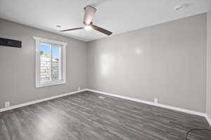 Empty room with dark wood-type flooring, ceiling fan, and a textured ceiling