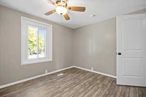 Empty room featuring a textured ceiling, dark wood-type flooring, and ceiling fan