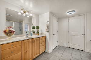 Bathroom with vanity, a textured ceiling, a shower with shower door, and tile patterned floors