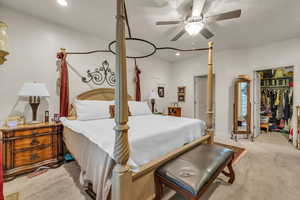 Carpeted bedroom with a closet, ceiling fan, and a spacious closet