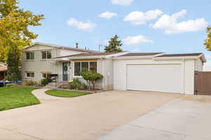 Split level home featuring a garage and a front lawn