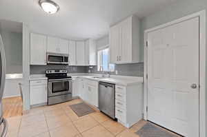 Kitchen featuring appliances with stainless steel finishes, white cabinets, and light tile patterned floors