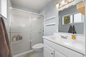 Bathroom featuring vanity, a shower with shower door, and toilet