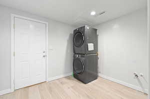 Washroom featuring stacked washer / drying machine and light wood-type flooring