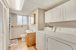 Laundry room featuring sink, light tile patterned flooring, and separate washer and dryer