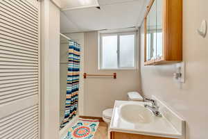 Bathroom with vanity, curtained shower, toilet, and tile patterned floors