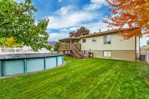 Back of property with central air condition unit, a pool side deck, a sunroom, and a lawn