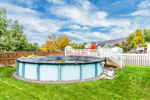 View of swimming pool with a lawn and a deck with mountain view