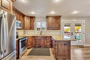 Kitchen with a wealth of natural light, sink, appliances with stainless steel finishes, and light hardwood / wood-style floors